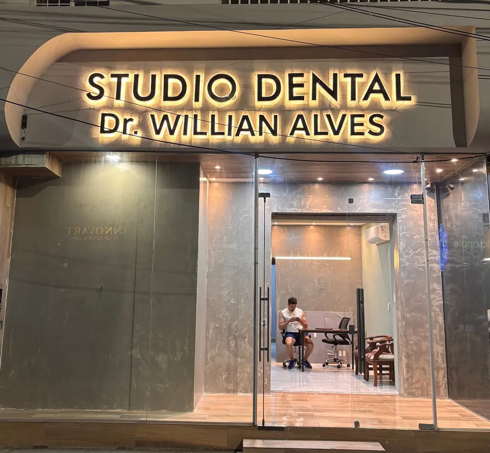 Fachada do Studio Dental Dr. Willian Alves à noite, com o letreiro aceso na Av. Guararapes