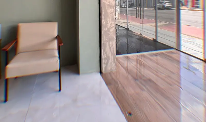 Recepção com poltrona, piso claro e porta de vidro para a avenida