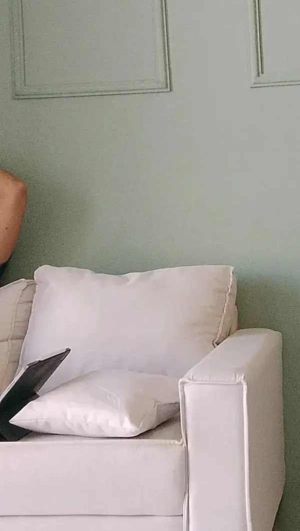 Sofá branco diante da parede verde com molduras